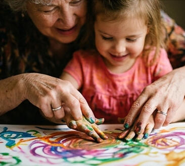 An image showing a grandmother painting with her granddaughter.